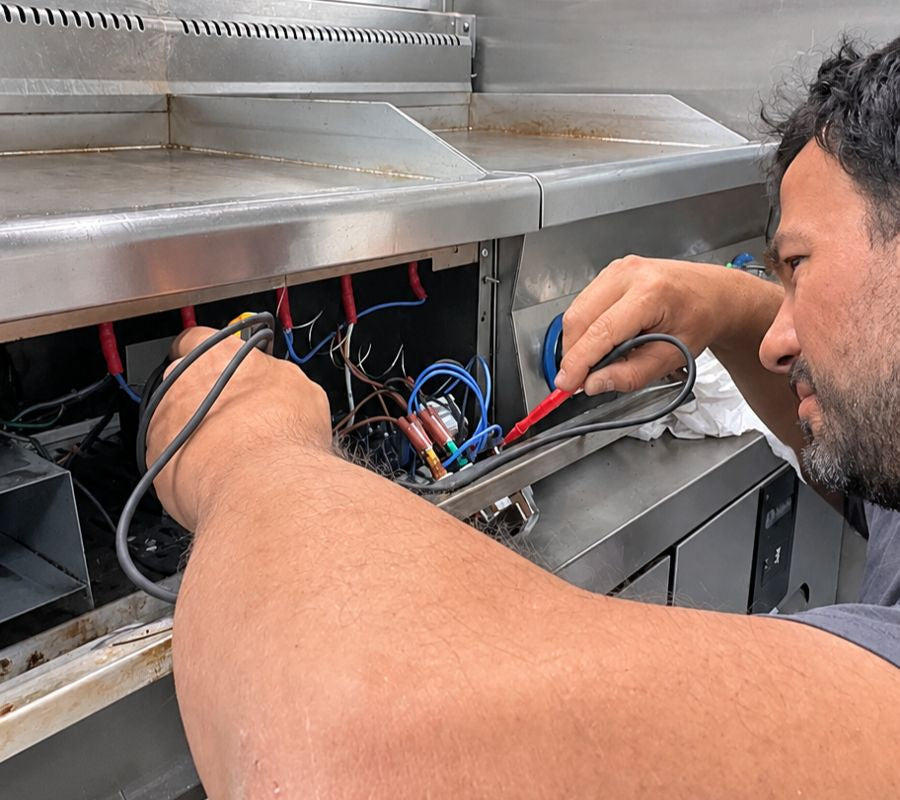 Techniker von gastrosystems prüft ein Gastrogerät mit dem Messgerät